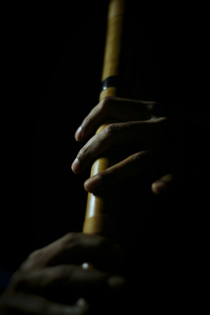 暗い中で竹笛を吹いている