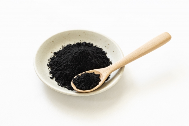 白い小皿に竹炭が木のスプーンに乗っている